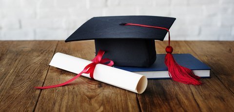 Cappello e pergamena di laurea su di un tavolo